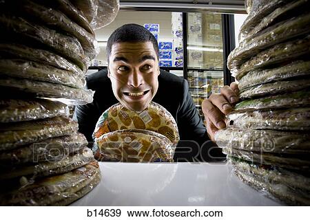 Stock Photo - Man holding pizzas at grocery store. Fotosearch