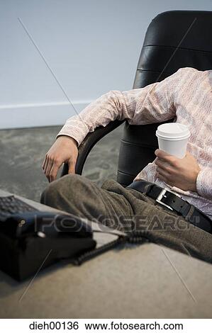Stock Photograph - Man in office holding coffee and waiting for phone call. Fotosearch