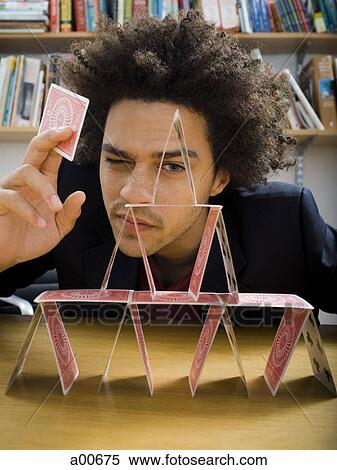 Stock Photography - Man making a pyramid out of playing cards. Fotosearch