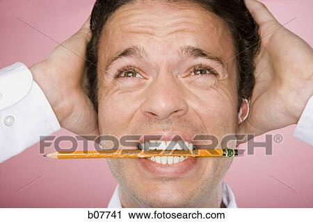 Stock Image - Man nervously chewing on pencil. Fotosearch