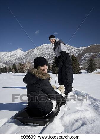 Man pulling woman on toboggan View Large Photo Image Stock Photo - Man pulling woman on toboggan. Fotosearch