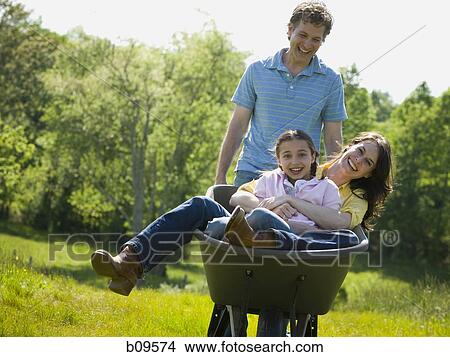 man pushing his daughter and his wife in a wheelbarrow View Large Photo Image Picture - man pushing his daughter and his wife in a wheelbarrow. Fotosearch