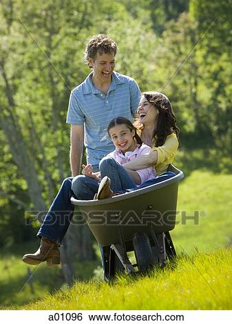 Man pushing his daughter and his wife in a wheelbarrow View Large Photo Image Stock Photograph - Man pushing his daughter and his wife in a wheelbarrow. Fotosearch