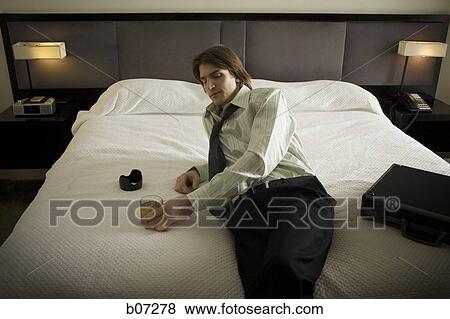 Man relaxing with a drink in hotel room View Large Photo Image Stock Photo - Man relaxing with a drink in hotel room. Fotosearch