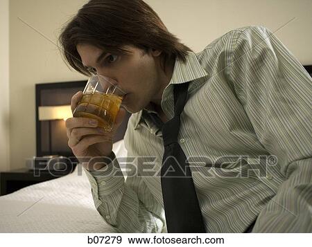 Man relaxing with a drink in hotel room View Large Photo Image Stock Photo - Man relaxing with a drink in hotel room. Fotosearch