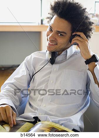 Man sitting and listening to headphones smiling View Large Photo Image Picture - Man sitting and listening to headphones smiling. Fotosearch