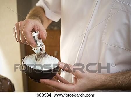 Picture - Mid section view of a man's hand mixing shaving cream with a brush in a bowl. Fotosearch