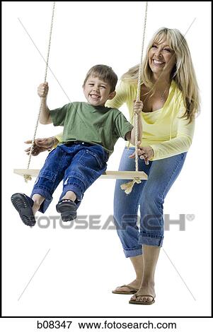 Mother Pushing Her Son On A Swing Stock Photo