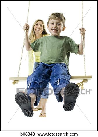 Mother pushing her son on a swing View Large Photo Image Stock Photo - Mother pushing her son on a swing. Fotosearch