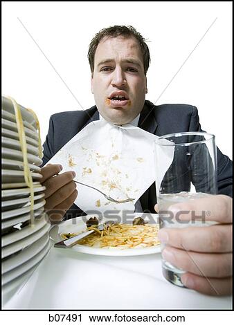 Stock Image - Overweight businessman gorging himself on spaghetti. Fotosearch