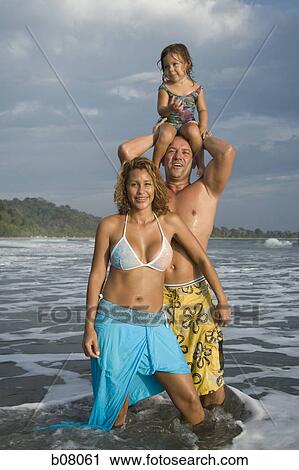 Stock Image - Parents playing with young daughter on beach. Fotosearch