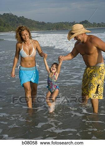 Parents playing with young daughter on beach View Large Photo Image Stock Photo - Parents playing with young daughter on beach. Fotosearch