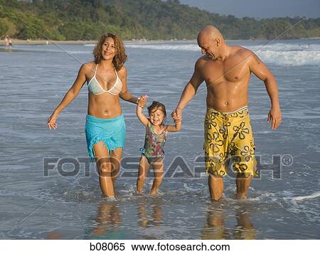 Stock Photography - Parents playing with young daughter on beach. Fotosearch