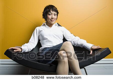 Portrait of a adult woman sitting on a chair and smiling View Large Photo Image Stock Photo - Portrait of a adult woman sitting on a chair and smiling. Fotosearch