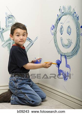 Stock Image - Portrait of a boy painting on a wall. Fotosearch