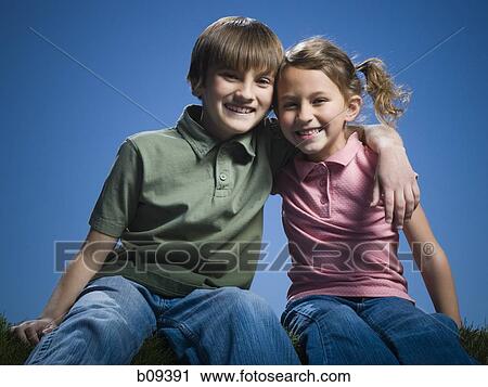 Stock Image - Portrait of a boy sitting with his arm around his sister. Fotosearch