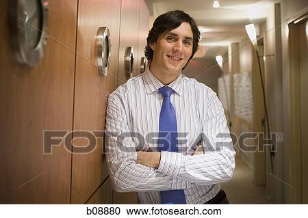 Stock Image - Portrait of a businessman leaning against a wooden wall with his arms crossed. Fotosearch