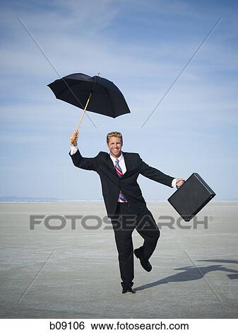 Stock Photograph - Portrait of a businessman smiling and holding an umbrella. Fotosearch