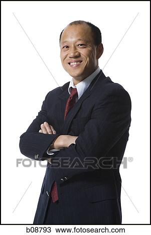 Stock Image - Portrait of a businessman standing with his arms folded and smiling. Fotosearch
