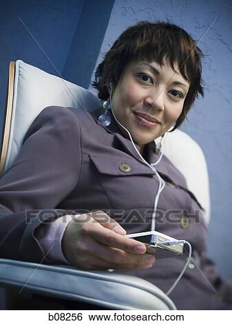 Portrait of a businesswoman listening to an MP3 player with headphones View Large Photo Image Stock Photograph - Portrait of a businesswoman listening to an MP3 player with headphones. Fotosearch