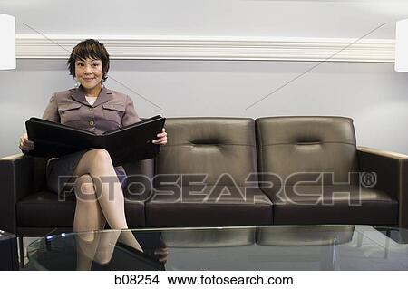 Portrait of a businesswoman sitting on a couch with a portfolio View Large Photo Image Picture - Portrait of a businesswoman sitting on a couch with a portfolio. Fotosearch