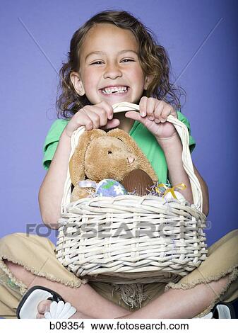 Picture - Portrait of a girl holding Easter eggs in a wicker basket. Fotosearch