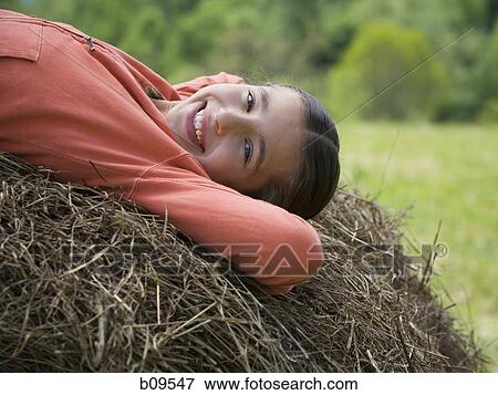 Portrait of a girl lying on a hay bale View Large Photo Image Stock Photo - Portrait of a girl lying on a hay bale. Fotosearch