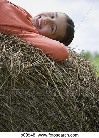 Portrait of a girl lying on a hay bale View Large Photo Image Stock Photo - Portrait of a girl lying on a hay bale. Fotosearch