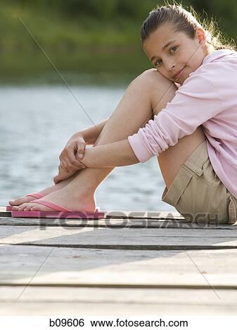 Portrait of a girl sitting on a pier View Large Photo Image Stock Photograph - Portrait of a girl sitting on a pier. Fotosearch