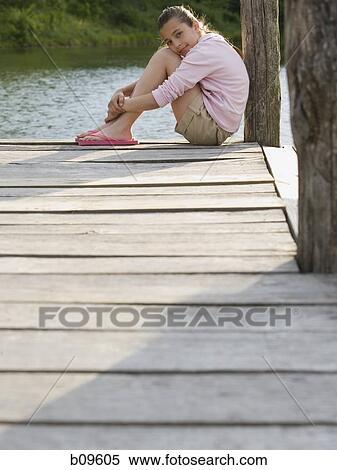Portrait of a girl sitting on a pier View Large Photo Image Stock Photography - Portrait of a girl sitting on a pier. Fotosearch