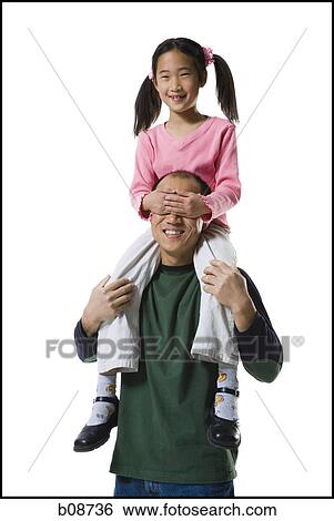 Stock Photograph - Portrait of a girl sitting on her father's shoulders, covering his eyes. Fotosearch