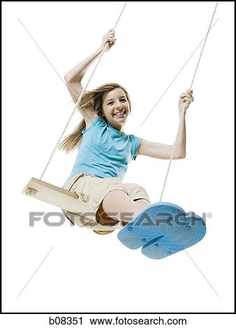 Stock Image - Portrait of a girl swinging on a rope swing. Fotosearch