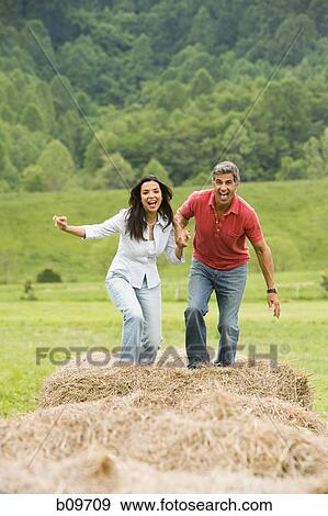 Portrait of a man and a woman running on hay bales View Large Photo Image Stock Photo - Portrait of a man and a woman running on hay bales. Fotosearch