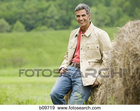 Portrait of a man leaning against a hay bale View Large Photo Image Stock Photo - Portrait of a man leaning against a hay bale. Fotosearch
