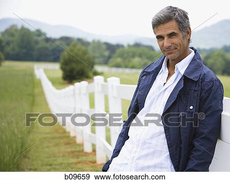 Portrait of a man leaning against a fence View Large Photo Image Stock Photo - Portrait of a man leaning against a fence. Fotosearch