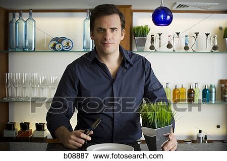 Portrait of a mid adult man holding a pair of scissors and herbs in a vase View Large Photo Image Stock Photo - Portrait of a mid adult man holding a pair of scissors and herbs in a vase. Fotosearch