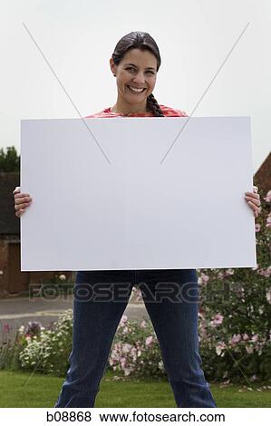 Portrait of a mid adult woman holding a blank sign and smiling View Large Photo Image Stock Photo - Portrait of a mid adult woman holding a blank sign and smiling. Fotosearch