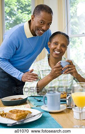 Stock Image - Portrait of a senior woman and a senior man smiling at the breakfast table. Fotosearch