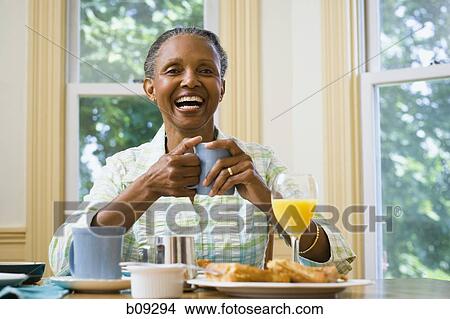 Picture - Portrait of a senior woman holding a cup of coffee at the breakfast table. Fotosearch