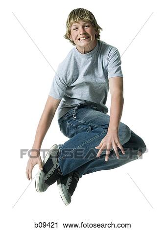 Stock Image - Portrait of a teenage boy jumping in mid air. Fotosearch