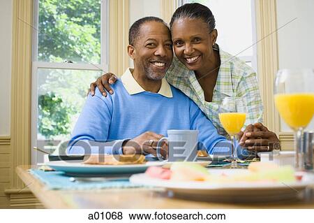 Stock Photo - Portrait of a woman and a man smiling at the breakfast table. Fotosearch