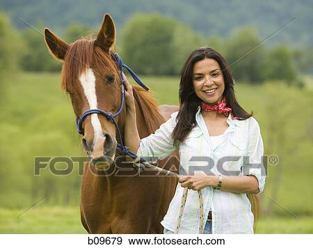 Portrait of a woman holding the reins of a horse View Large Photo Image Stock Photo - Portrait of a woman holding the reins of a horse. Fotosearch