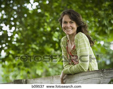 Portrait of a woman leaning on a wooden fence View Large Photo Image Stock Photo - Portrait of a woman leaning on a wooden fence. Fotosearch