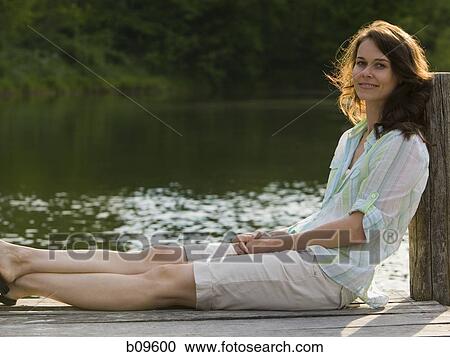 Portrait of a woman sitting on a pier View Large Photo Image Stock Image - Portrait of a woman sitting on a pier. Fotosearch