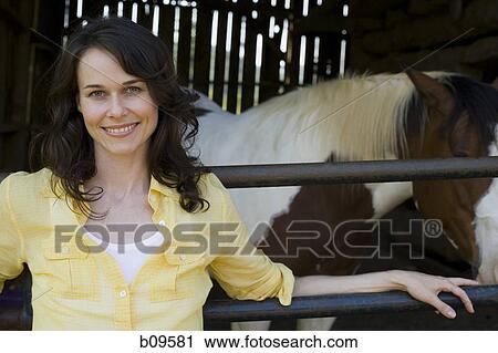 Stock Image - Portrait of a woman standing in front of a barn. Fotosearch