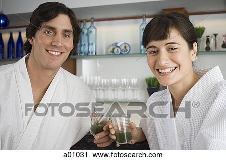Stock Image - Portrait of a young couple holding glasses of wheatgrass juice. Fotosearch