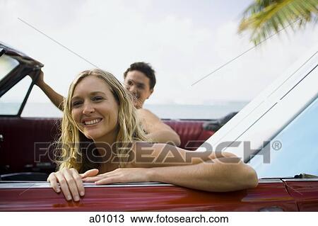 Stock Image - Portrait of a young couple sitting in a car. Fotosearch
