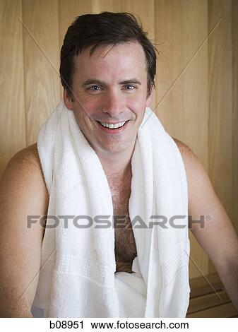 Stock Image - Portrait of a young man sitting in a sauna. Fotosearch
