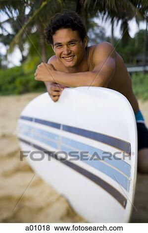 Portrait of a young man smiling and leaning against a surfboard View Large Photo Image Stock Photo - Portrait of a young man smiling and leaning against a surfboard. Fotosearch