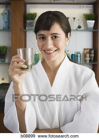 Portrait of a young woman holding a glass of wheatgrass juice View Large Photo Image Stock Photo - Portrait of a young woman holding a glass of wheatgrass juice. Fotosearch